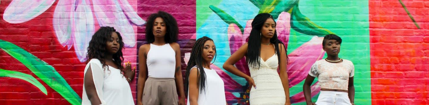 six women wearing white pants posing