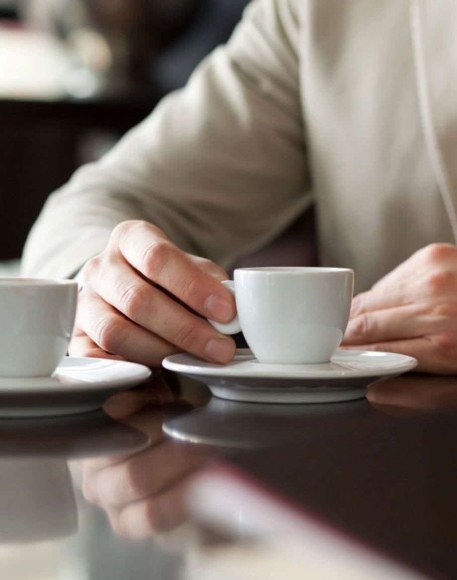 A person holds a white coffee cup