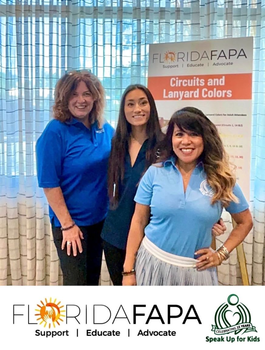 Three women stand in front of a Florida FAPA banner with a textured curtain in the background.
