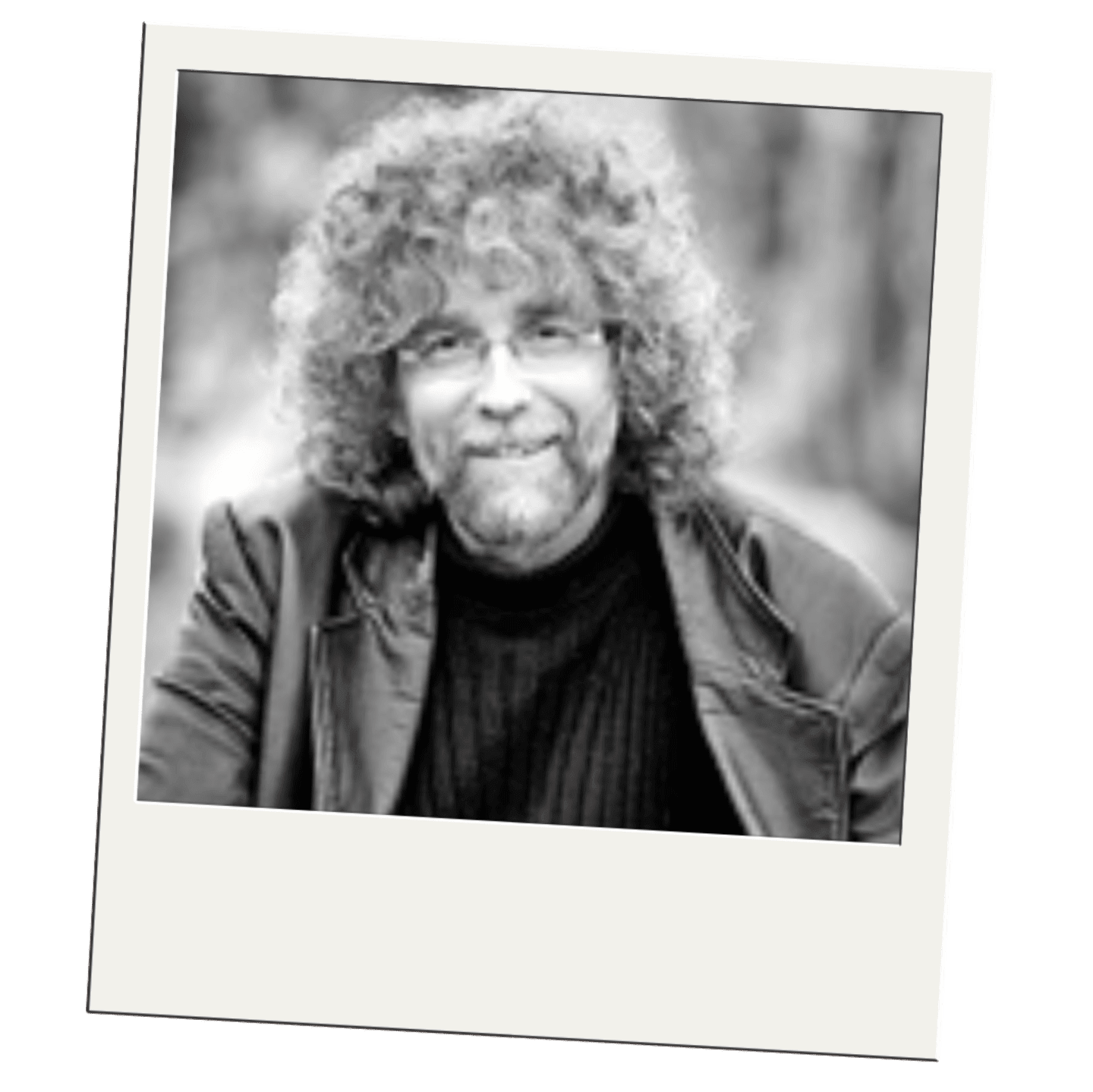 A black and white portrait of a man with curly hair and glasses is set against a blurred outdoor background.