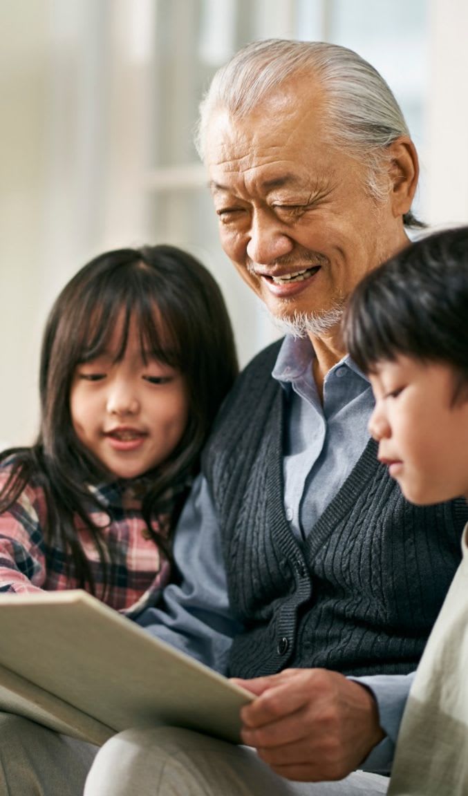 An elderly man reads to two young children