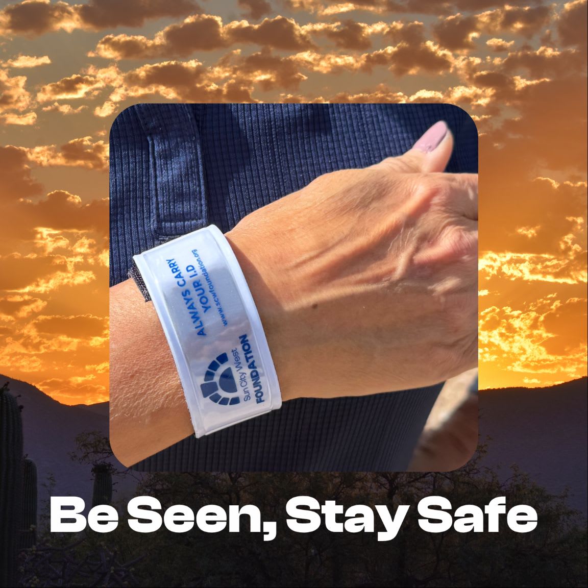 A person's wrist wearing a white identification band is centered against a backdrop of a golden sunset sky and dark silhouettes of mountains and cacti.