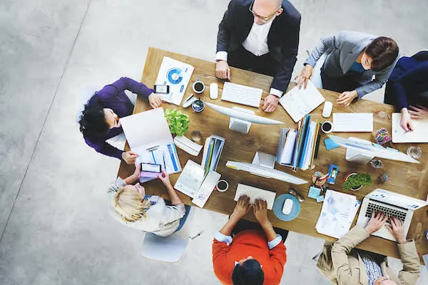 Personas en una mesa revisando reportes y tomando decisiones.