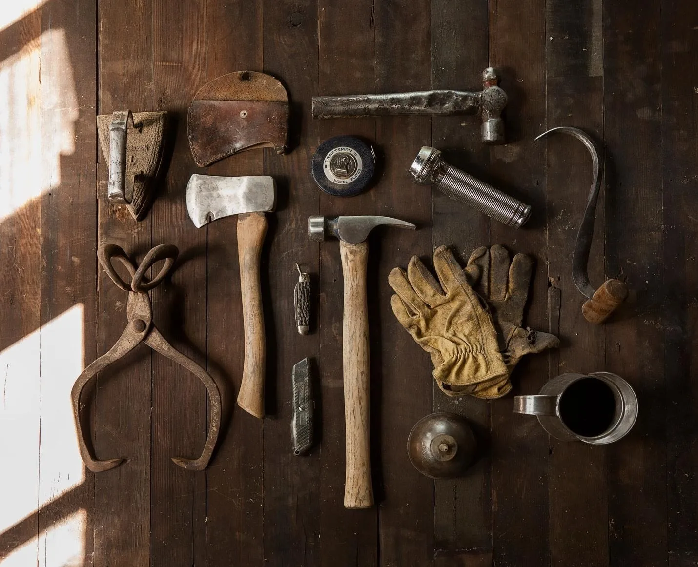 a table with tools on them, including a hammer, mallet, gloves, iron, and more