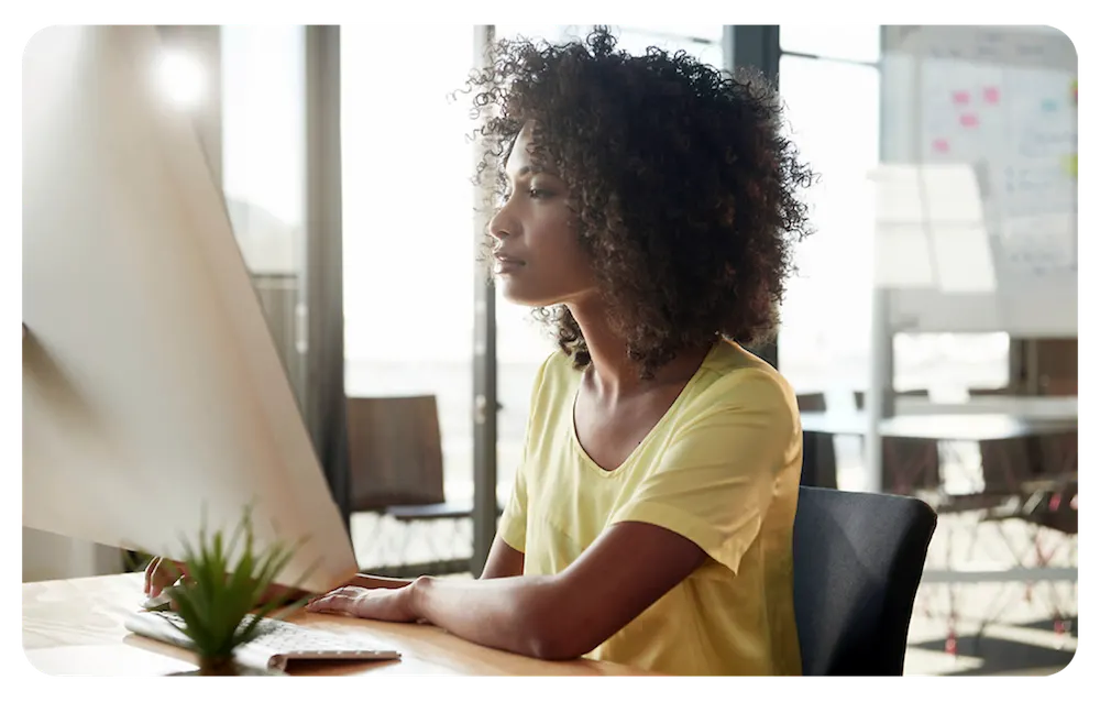 A woman working on a computer at her desk