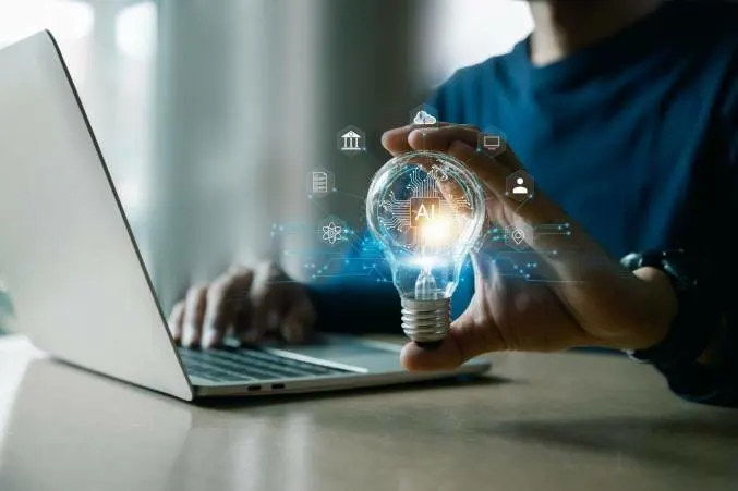 Person holding light bulb with AI lettering representing the aid AI can provide in decision-making.