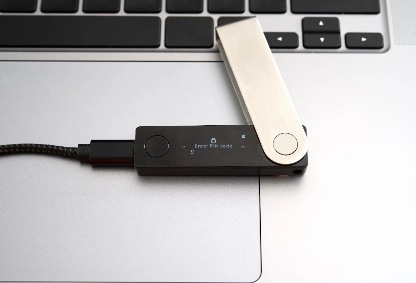 Hardware wallet connected to a laptop with Enter PIN code on the screen and a 9 entered with seven more spaces
