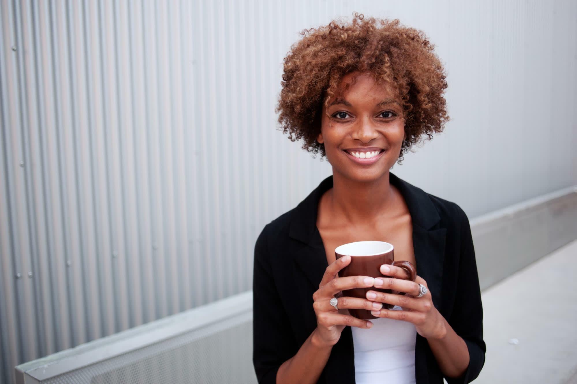 Person smiling, holding a coffee cup