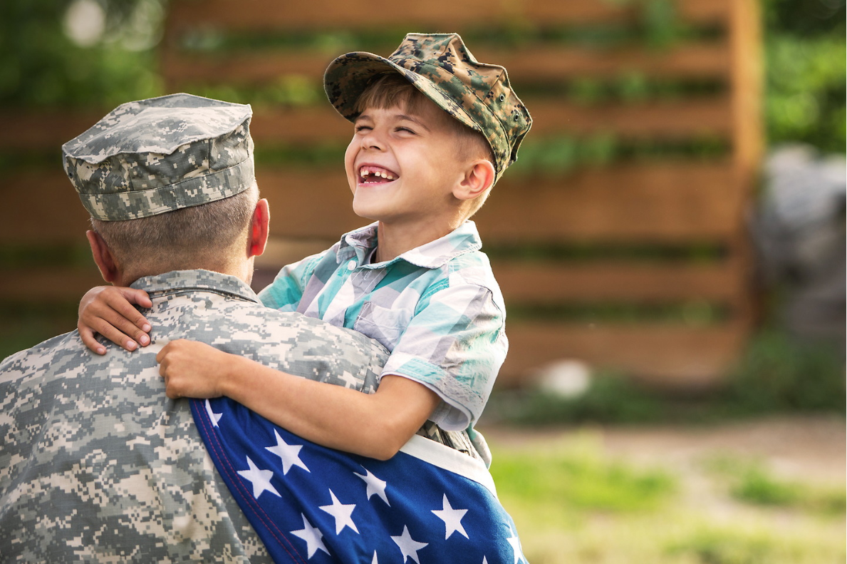 A child hugging a veteran with the American flag.