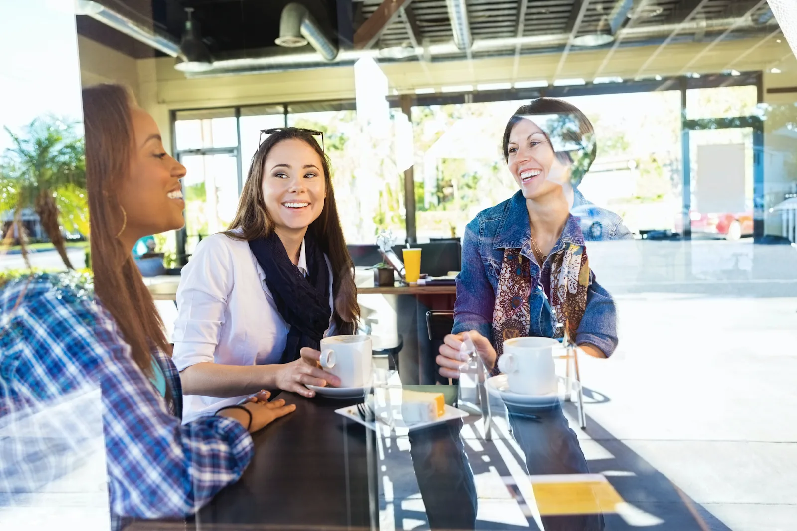 Three women sharing a laugh while seated at a table at Scott’s Restaurant and Bar.