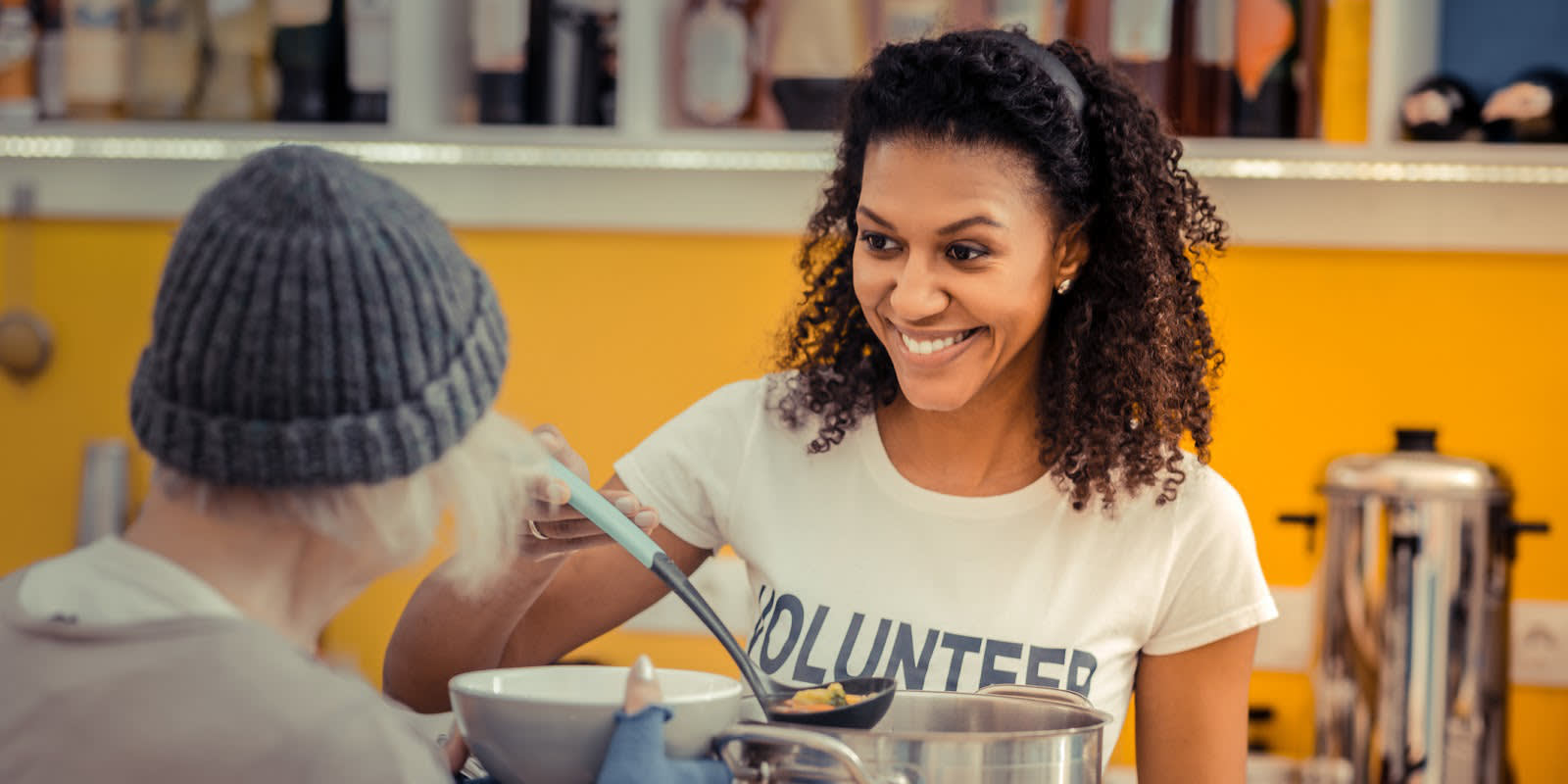 A woman volunteering to serve food to a person experiencing homelessness.