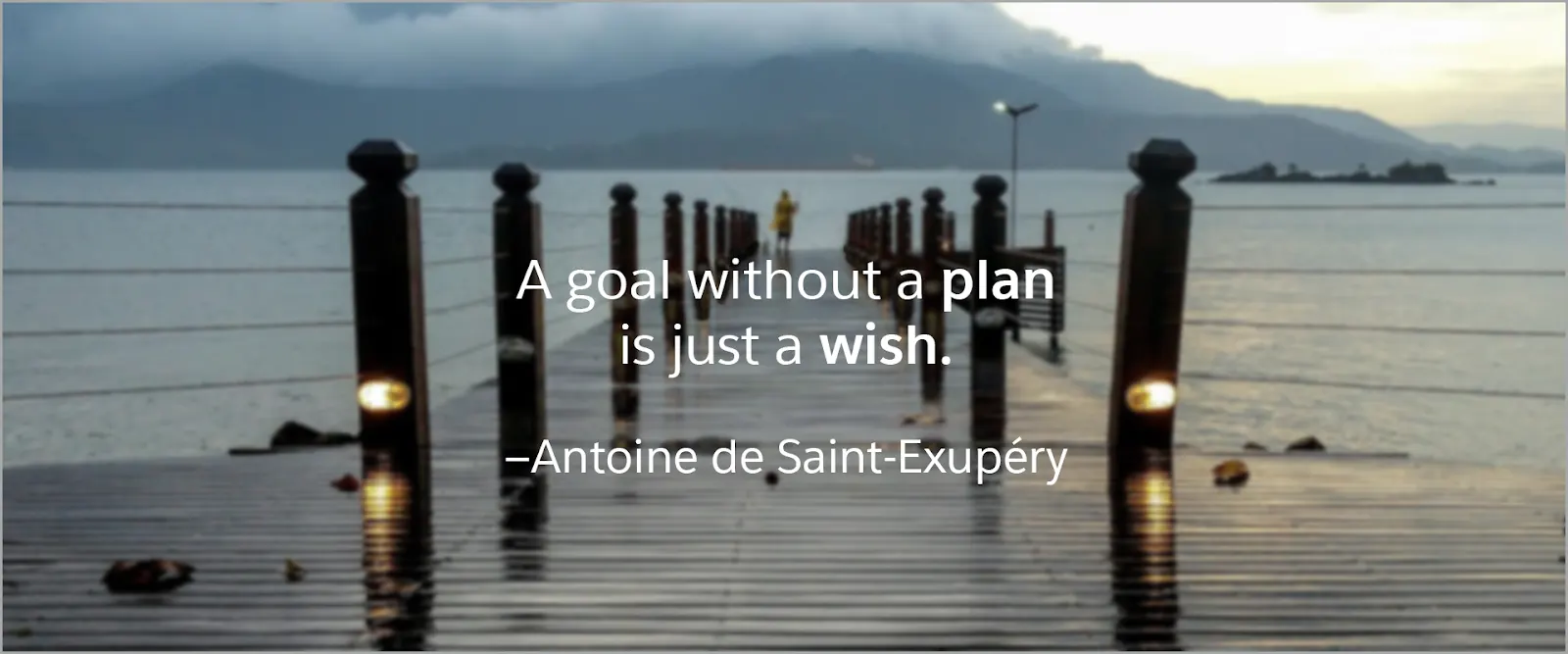 A dock extending into a cloud-covered lake. Text says, “A goal without a plan is just a wish.” –Antoine de Saint-Exupéry.