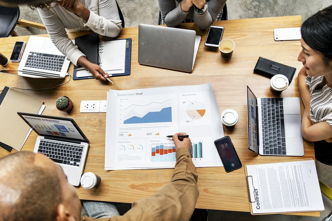 A sales operations team of four reviewing metrics printout on a table.