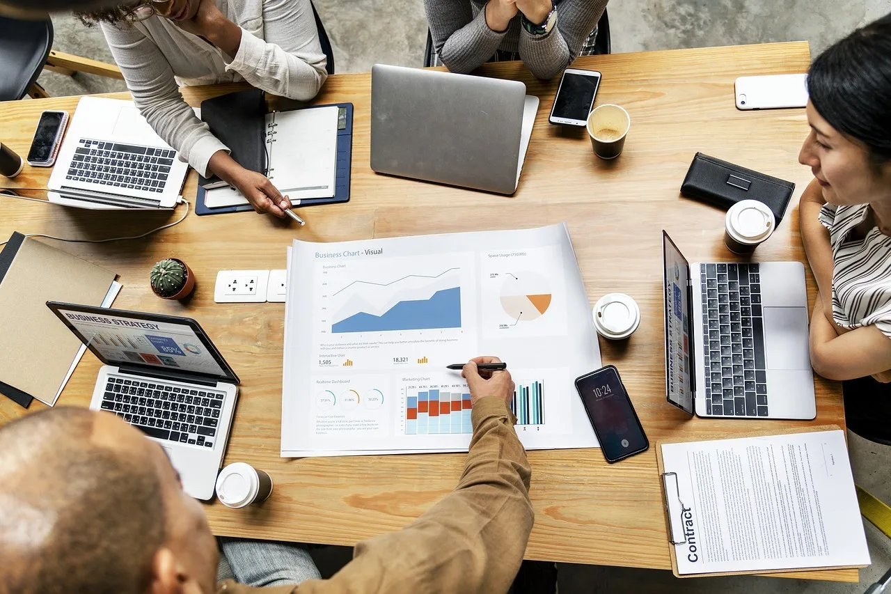 Une équipe des opérations commerciales composée de quatre personnes examinant une feuille avec des métriques sur une table.