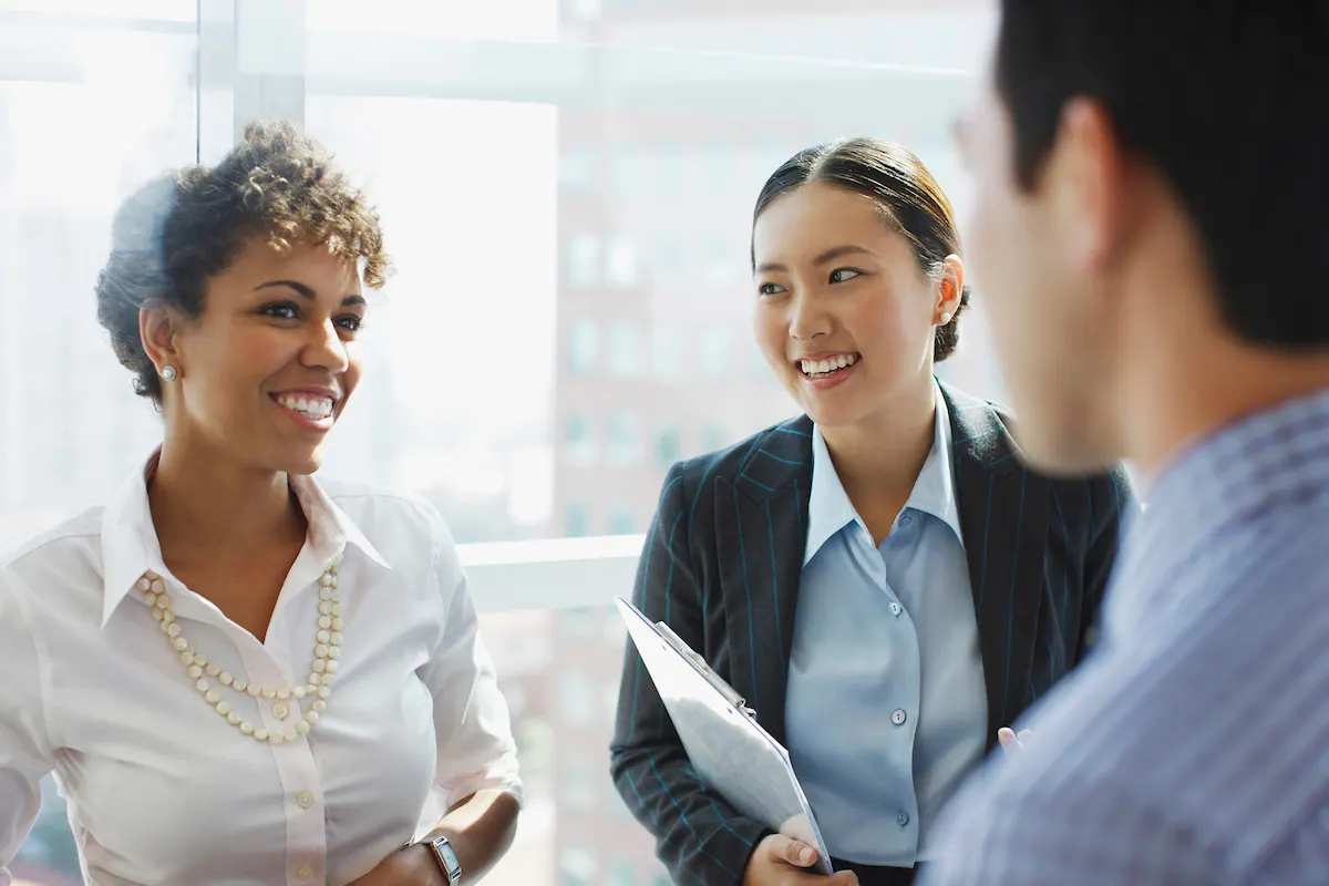 Trois professionnels des opérations commerciales souriant pendant une réunion.