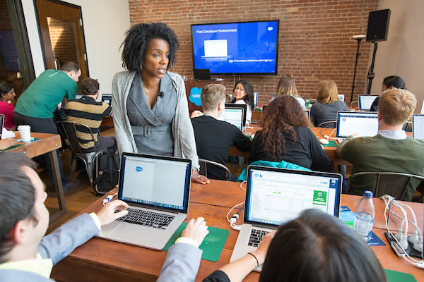 An instructor interacts with a classroom full of students with laptop computers.