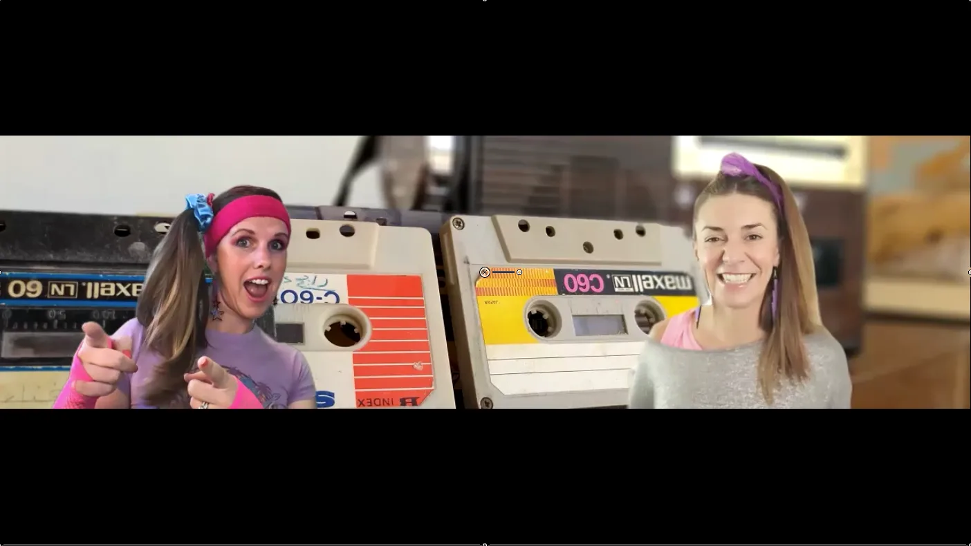 Two women dressed in 1980s athletic wear and sweatbands are pictured in split screen, with the woman on the left pointing both index fingers towards the camera.