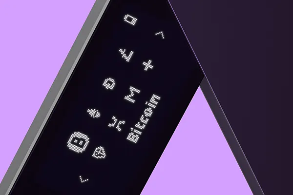 Closeup of Ledger NanoX hardware wallet with multiple blockchain icons on its screen, Bitcoin is selected.