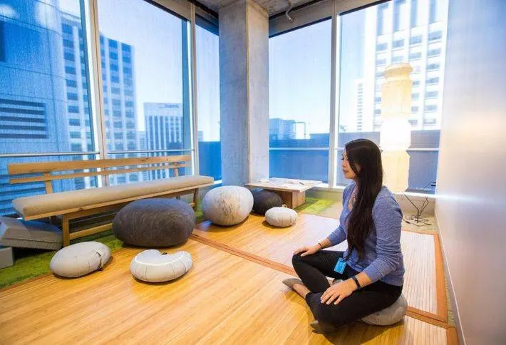 Image d’un espace de méditation Salesforce avec une personne assise en tailleur sur un sol en bois en train de méditer.