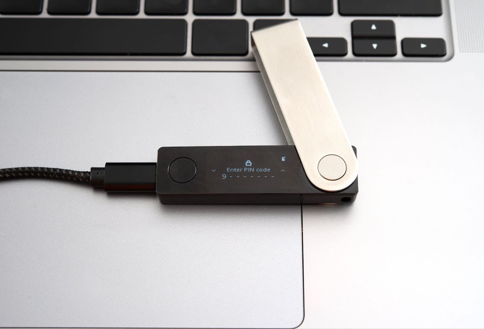 Hardware wallet connected to a laptop with Enter PIN code on the screen and a 9 entered with seven more spaces