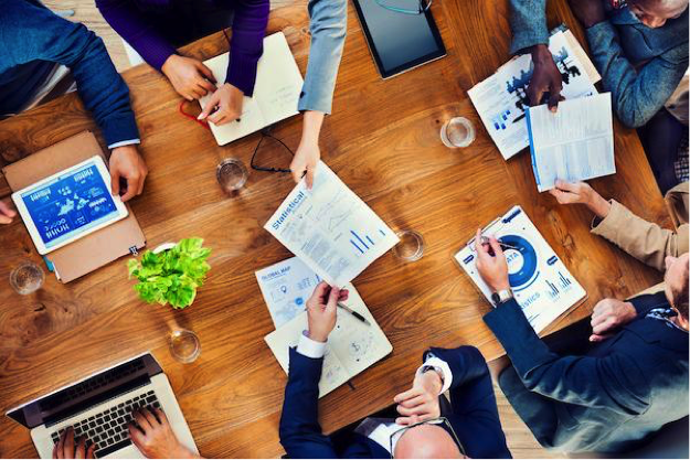 A meeting around a table with lots of papers