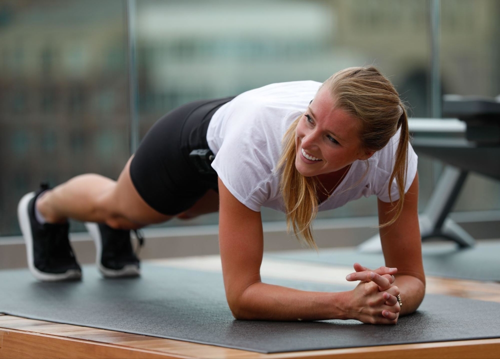 A dedicated female gym-goer focuses on her workout, pushing herself to  achieve her fitness goals through a variety of exercises and equipment.  Doing push-ups. Stock Photo
