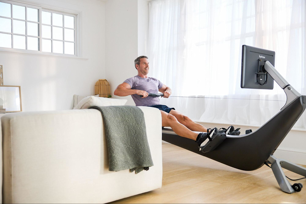 Man works out on a rowing machine to cross-train with other sports.