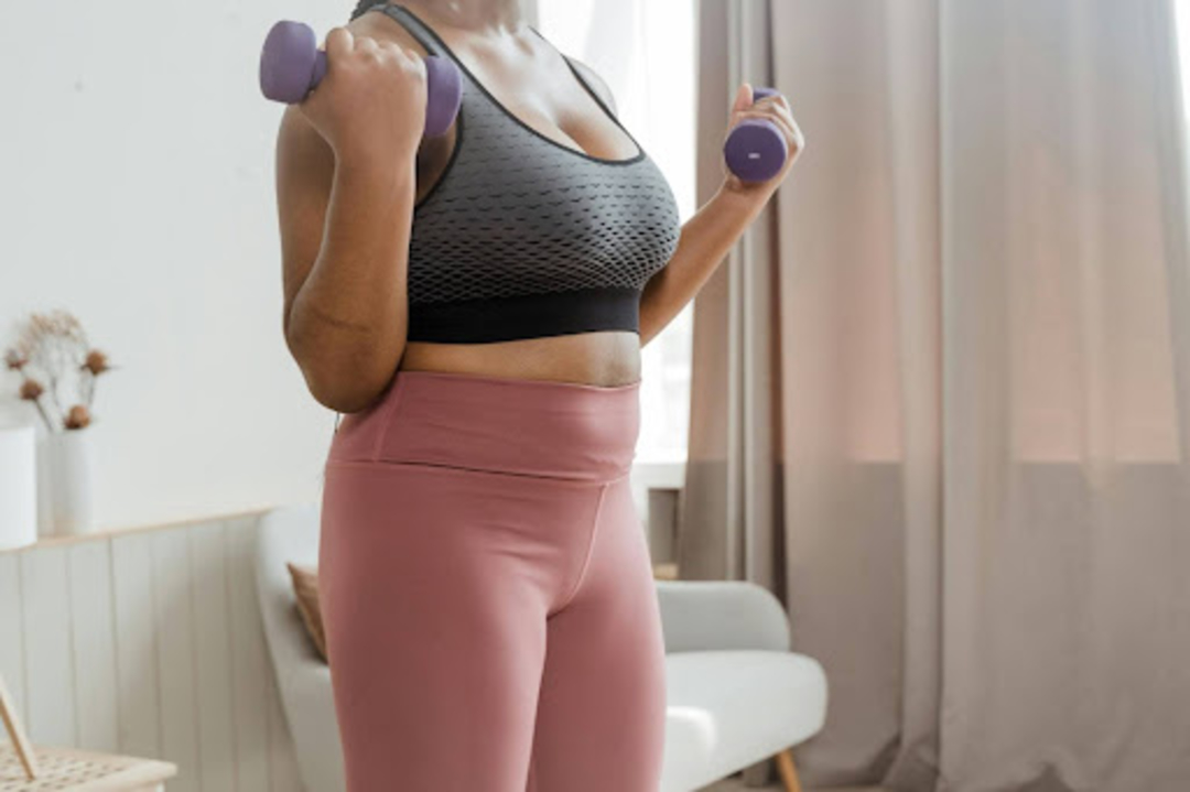 Busy woman does a dumbbell strength training workout at home.