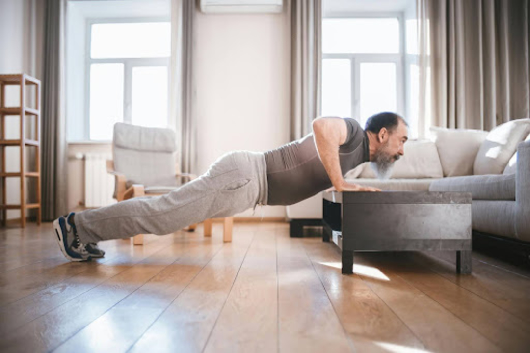 Man does a plank at home, a common chest exercise for beginners.