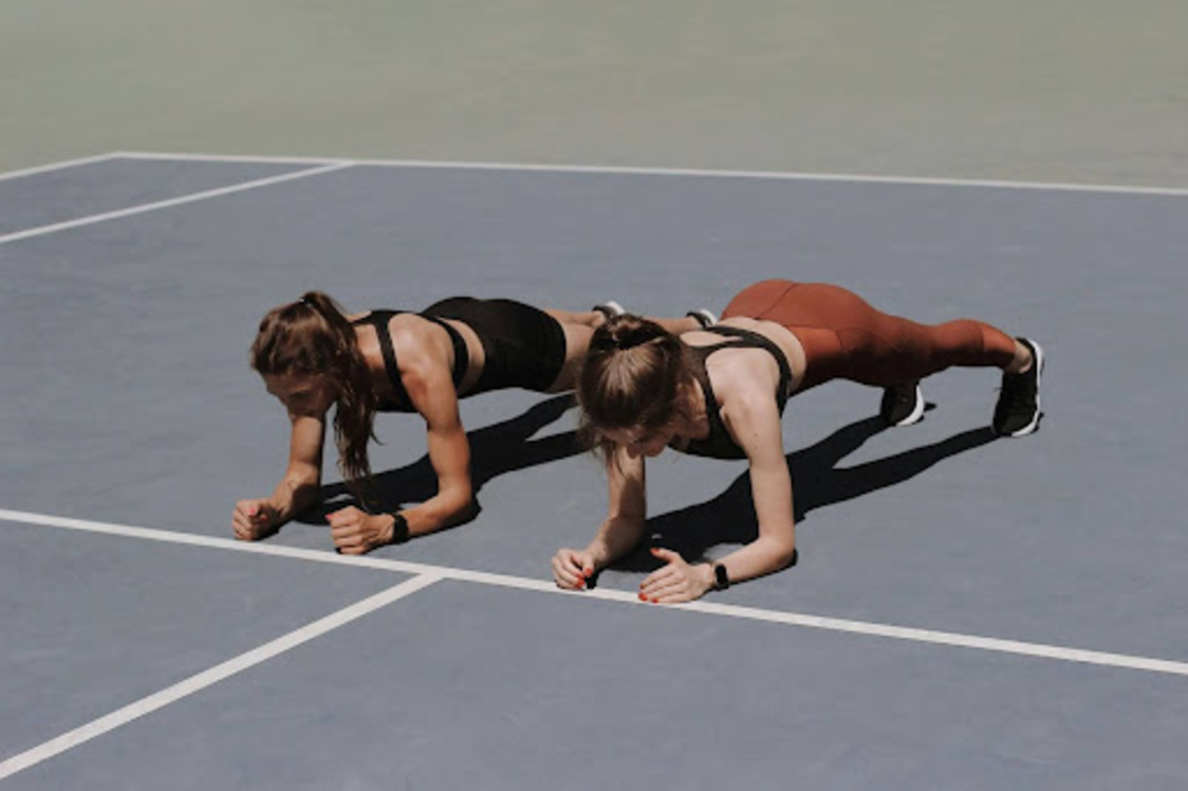 Two women do planks outdoors to bust the myth that strength training can make you bulky.