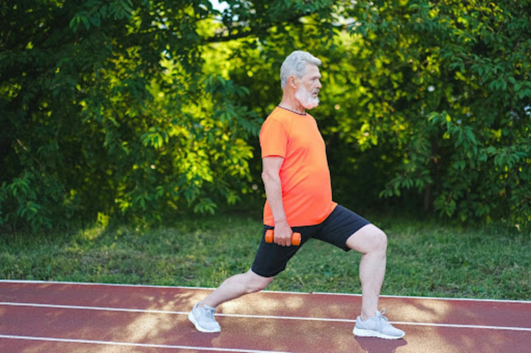 Man does beginner dumbbell exercises outdoors.