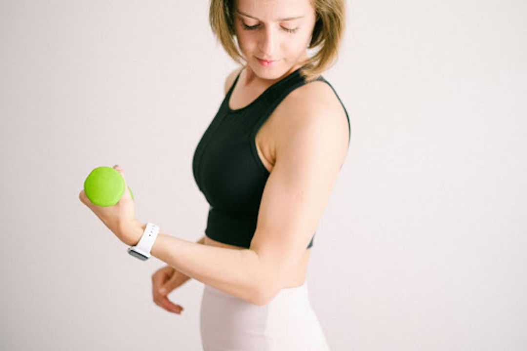 Busy woman does a strength training workout with a green dumbbell.