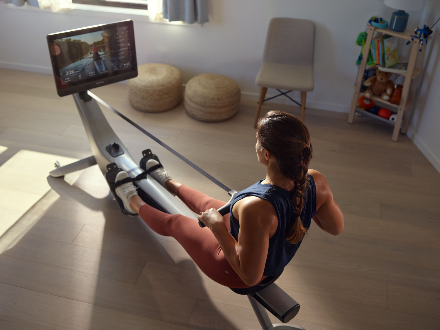 Woman works out using a Hydrow rowing machine in her home gym.