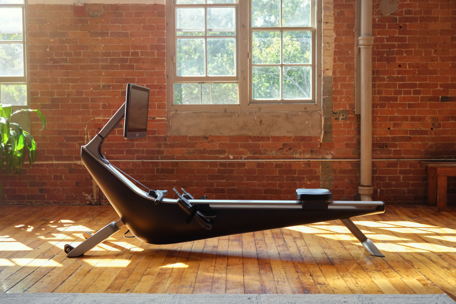 A Hydrow rowing machine inside a home with brick walls.