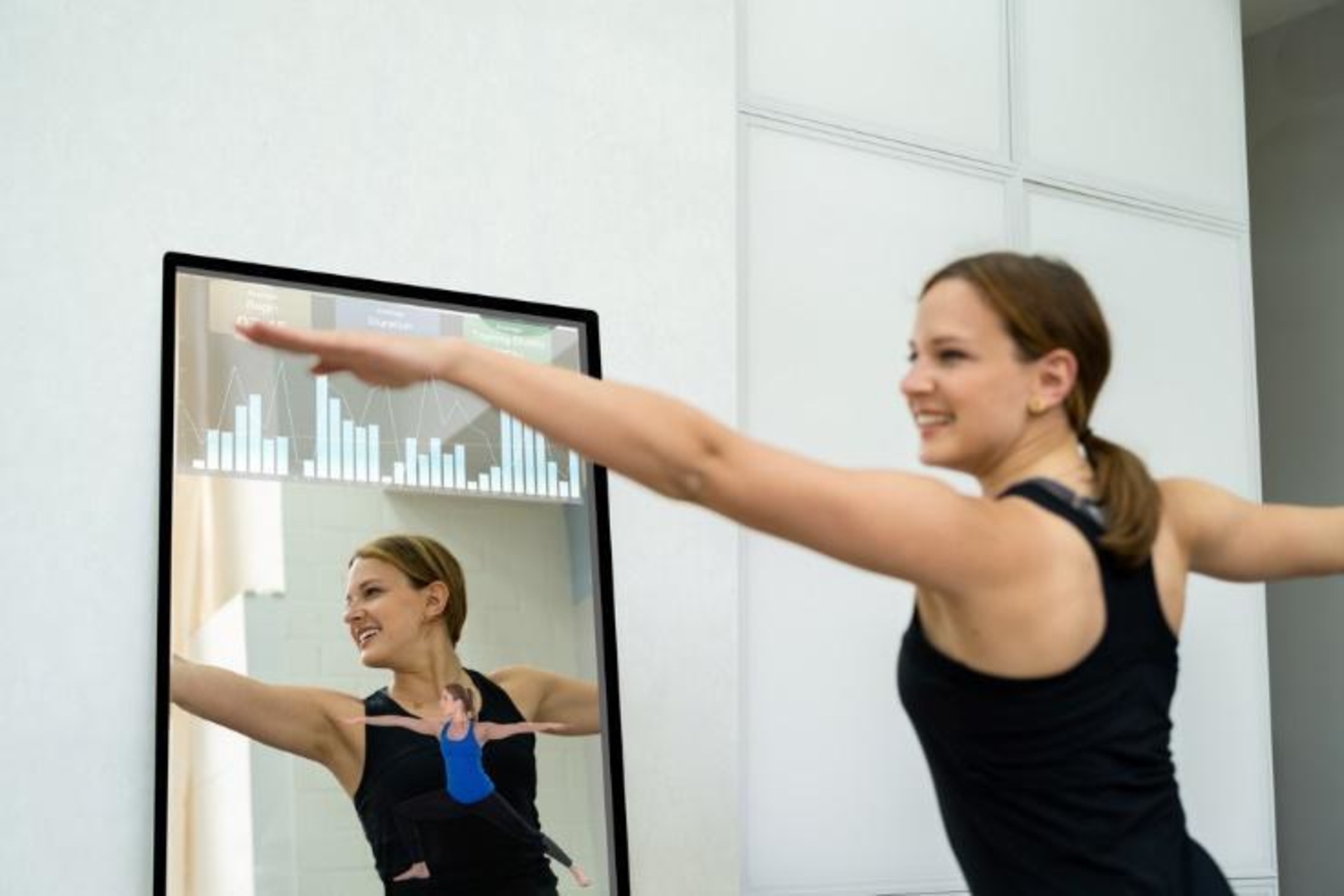 Woman works out in front of a workout mirror, known as the best home exercise equipment pieces.