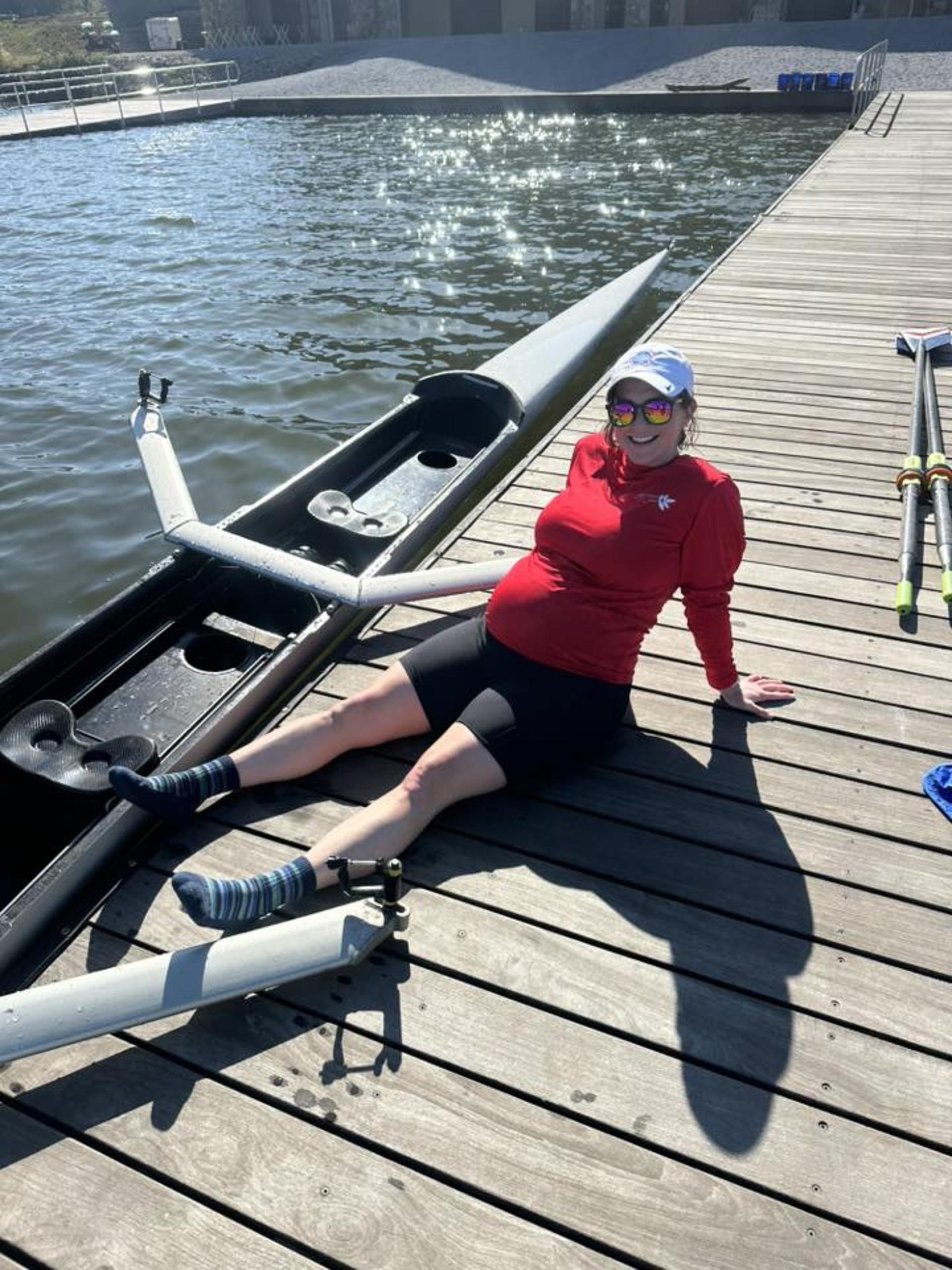 Hydrow Member Charlotte Rose sits next to her scull at 30 weeks pregnant.