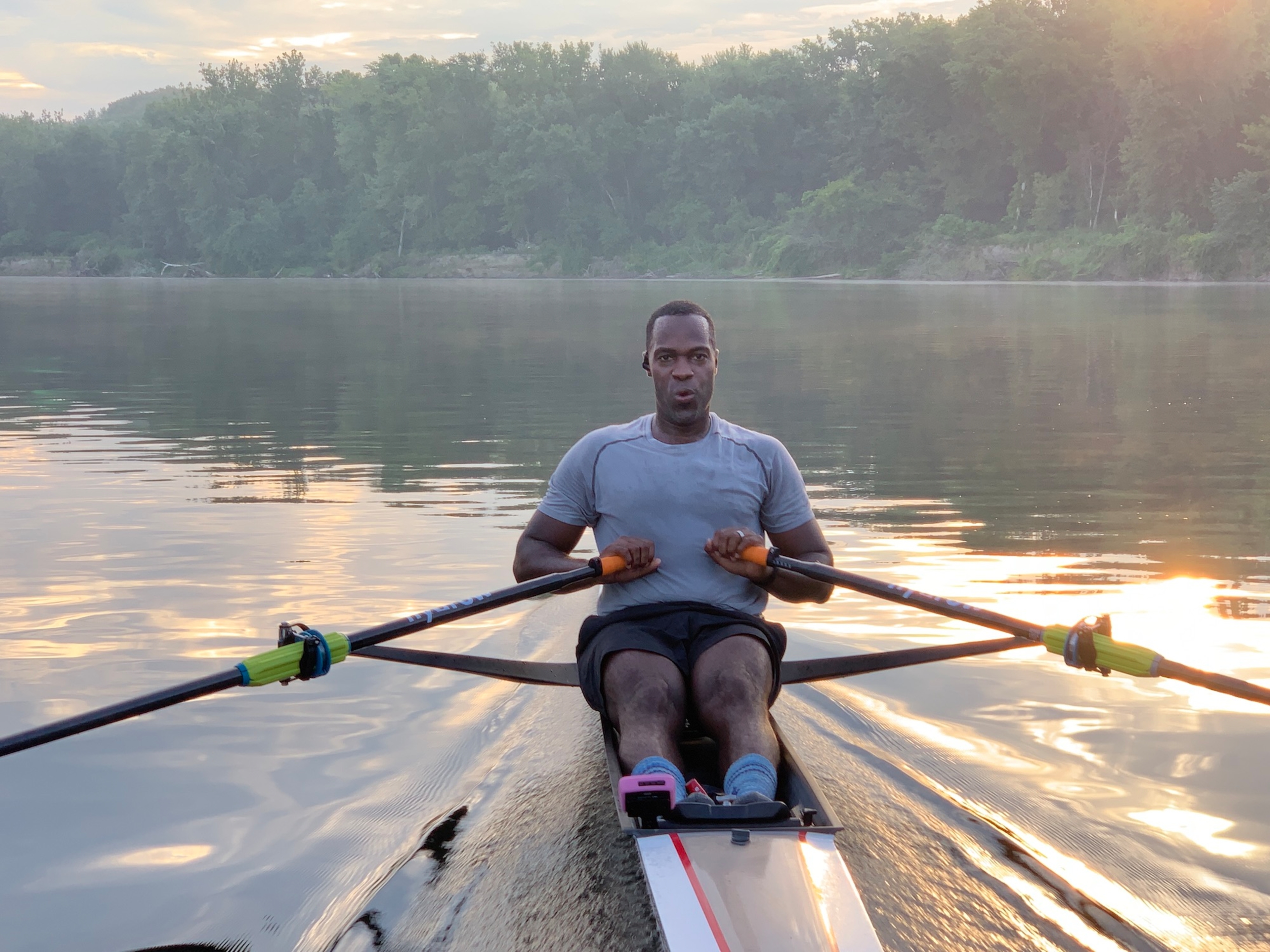 Hydrow Athlete rows on the water as part of a HIIT rowing workout.
