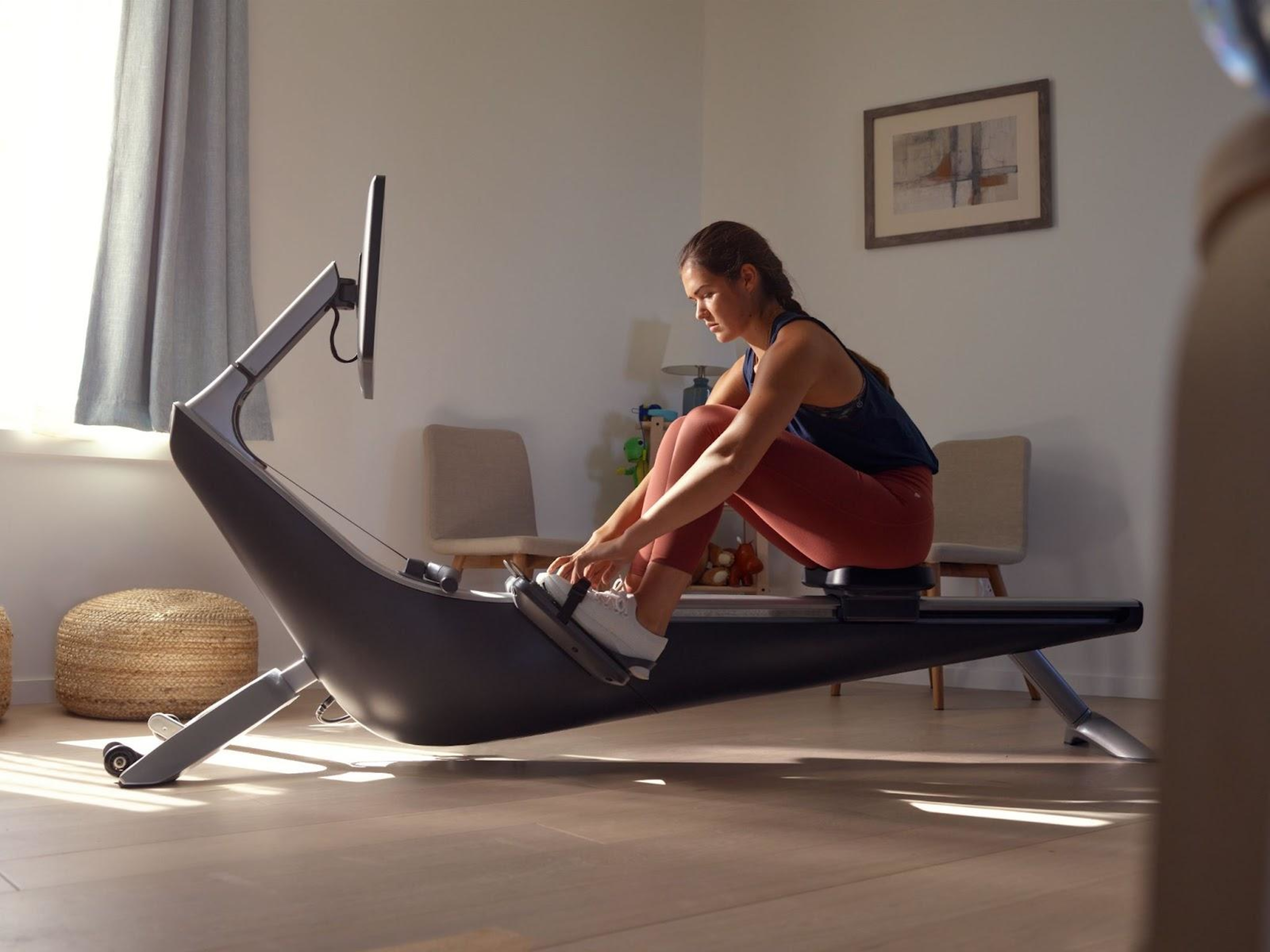 Woman ties her shoes on her rowing machine.