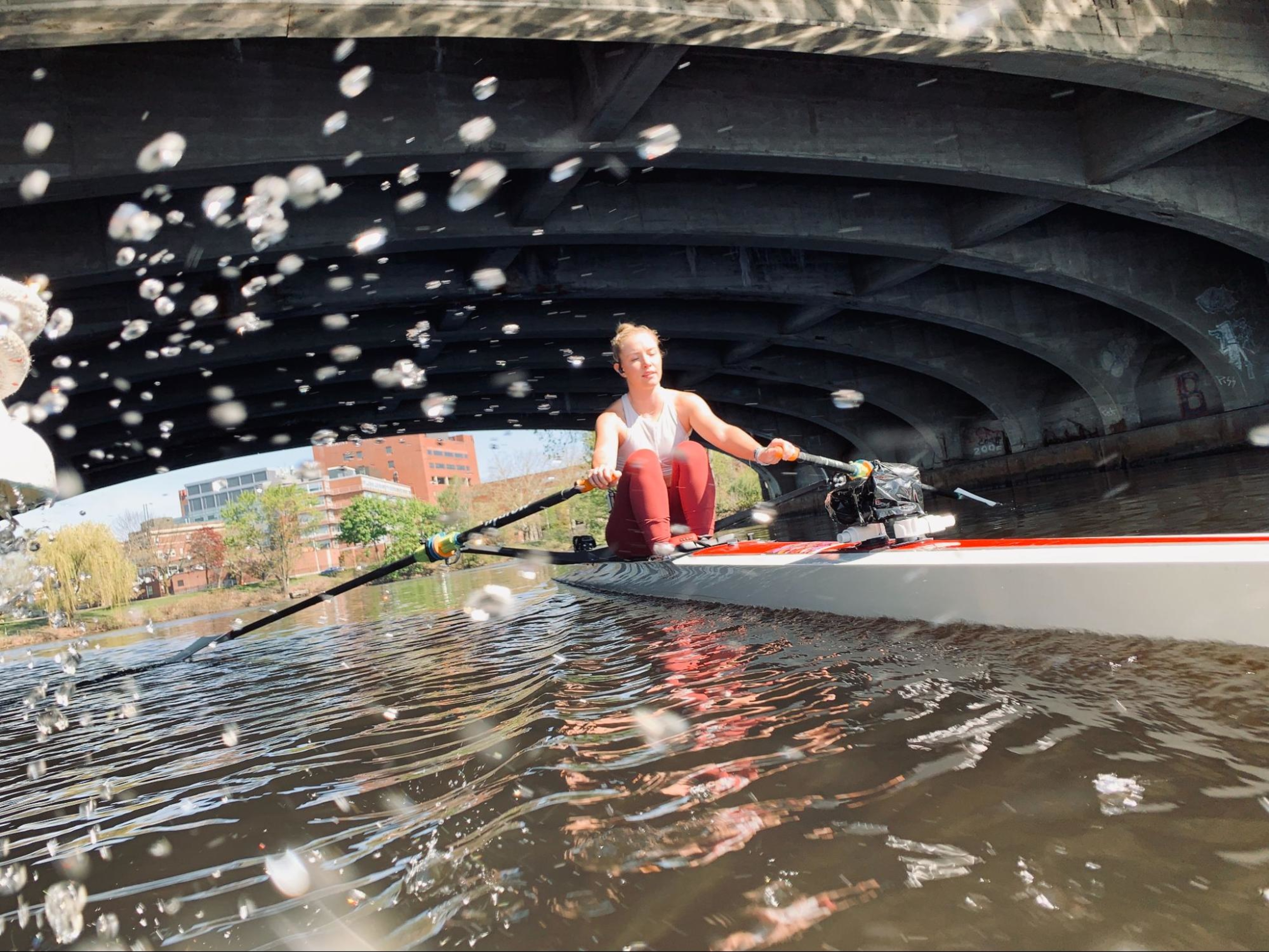 Woman rows on a river and works on improving her rowing pace.