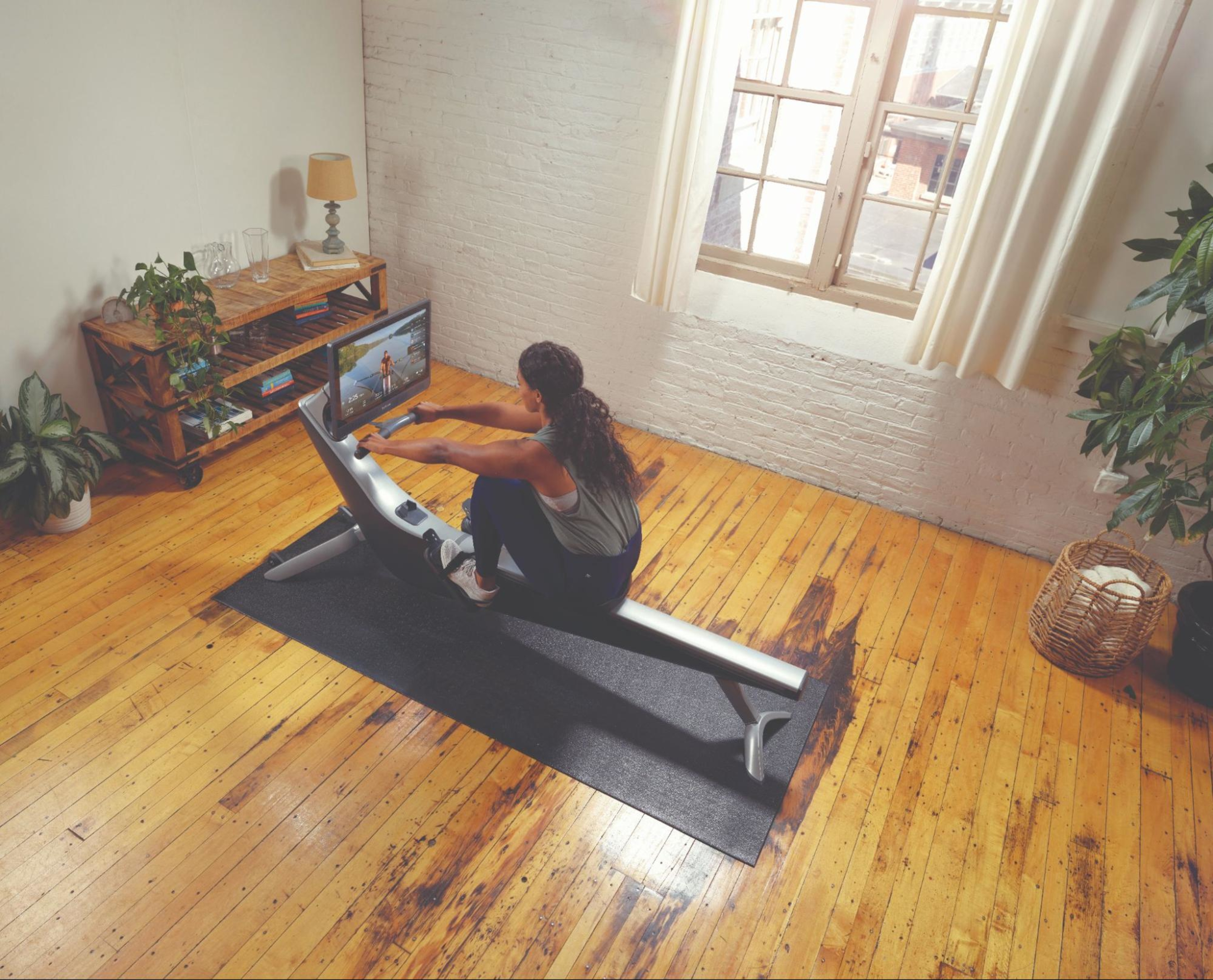 Woman works out on her Hydrow rowing machine and tries to improve her rowing machine pace.