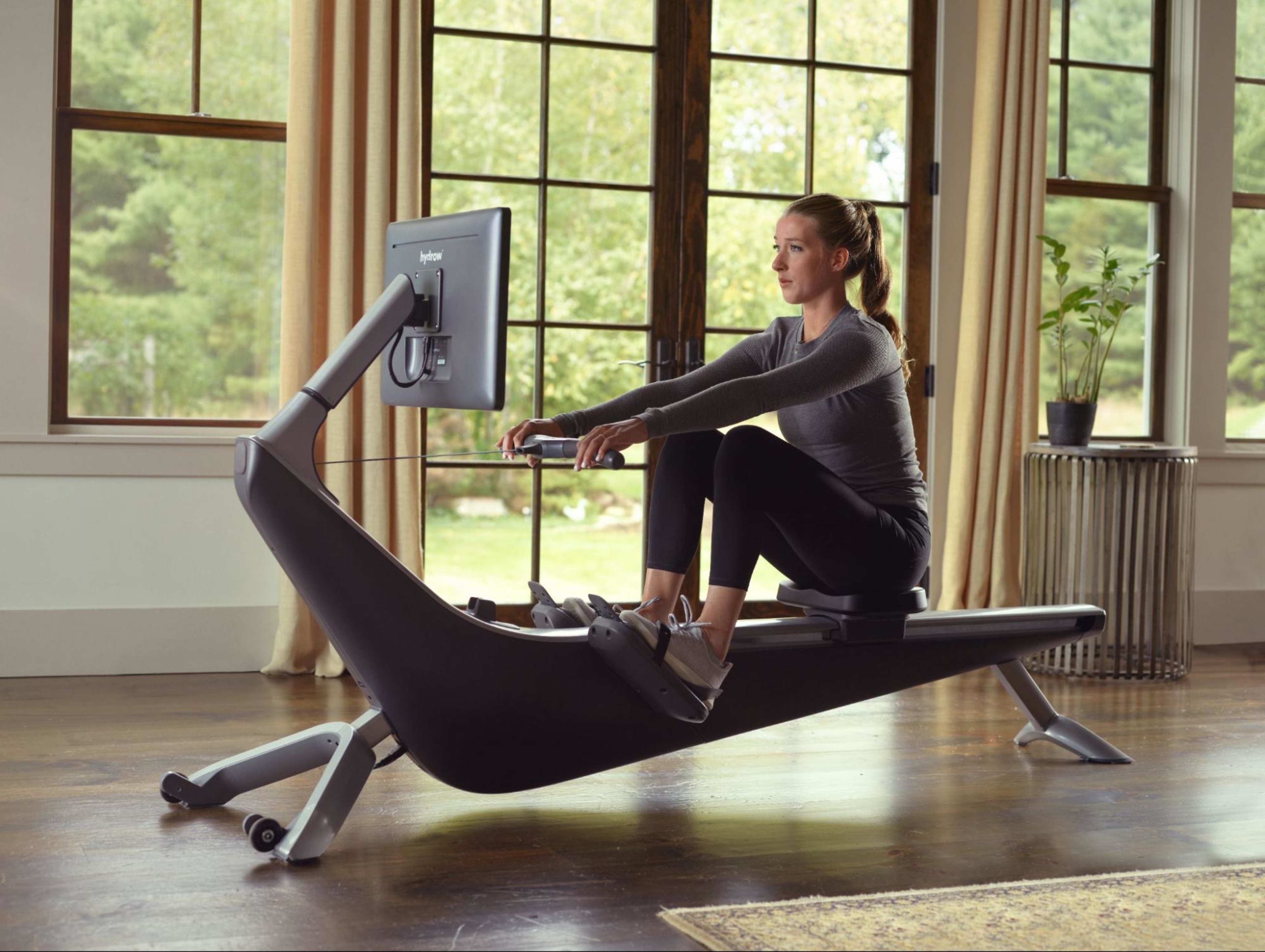 Woman works out on her indoor rowing machine and tries to improve her rowing pace.