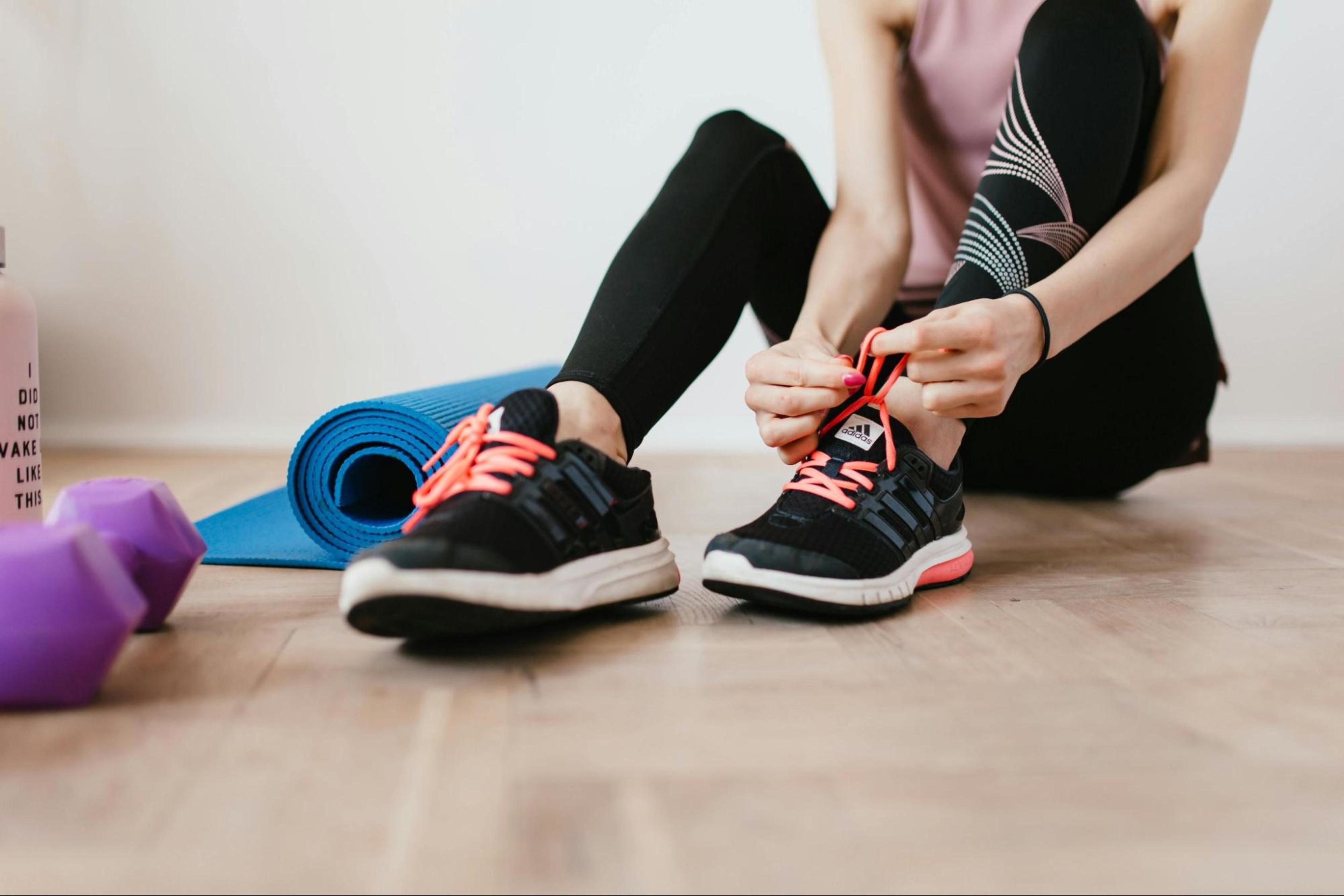 Woman laces up her sneakers and gets ready to work out at home.