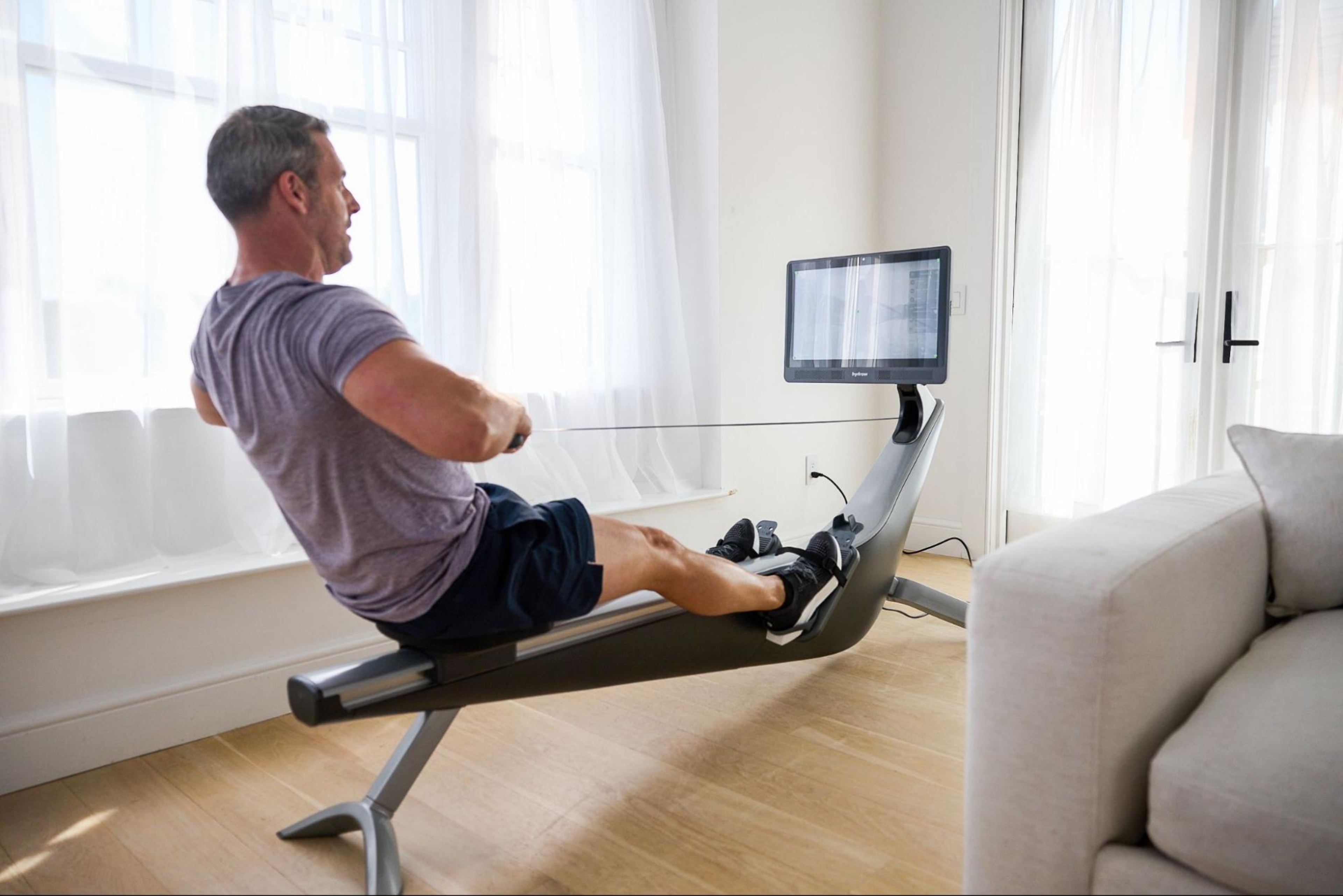 Man uses proper form to avoid lower-back strain from rowing, a common rowing machine injury.