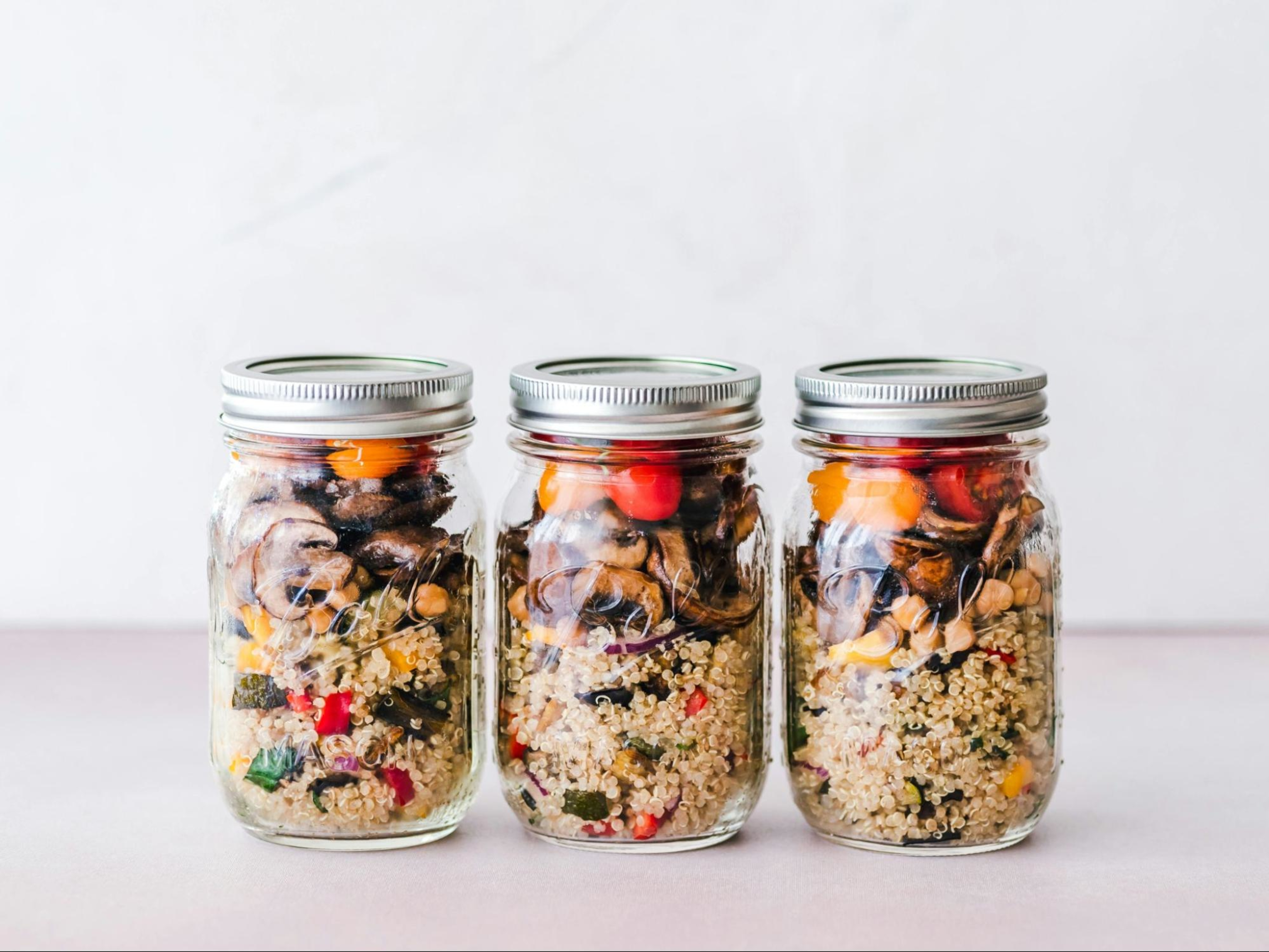 Mason jars filled with quinoa and veggies.