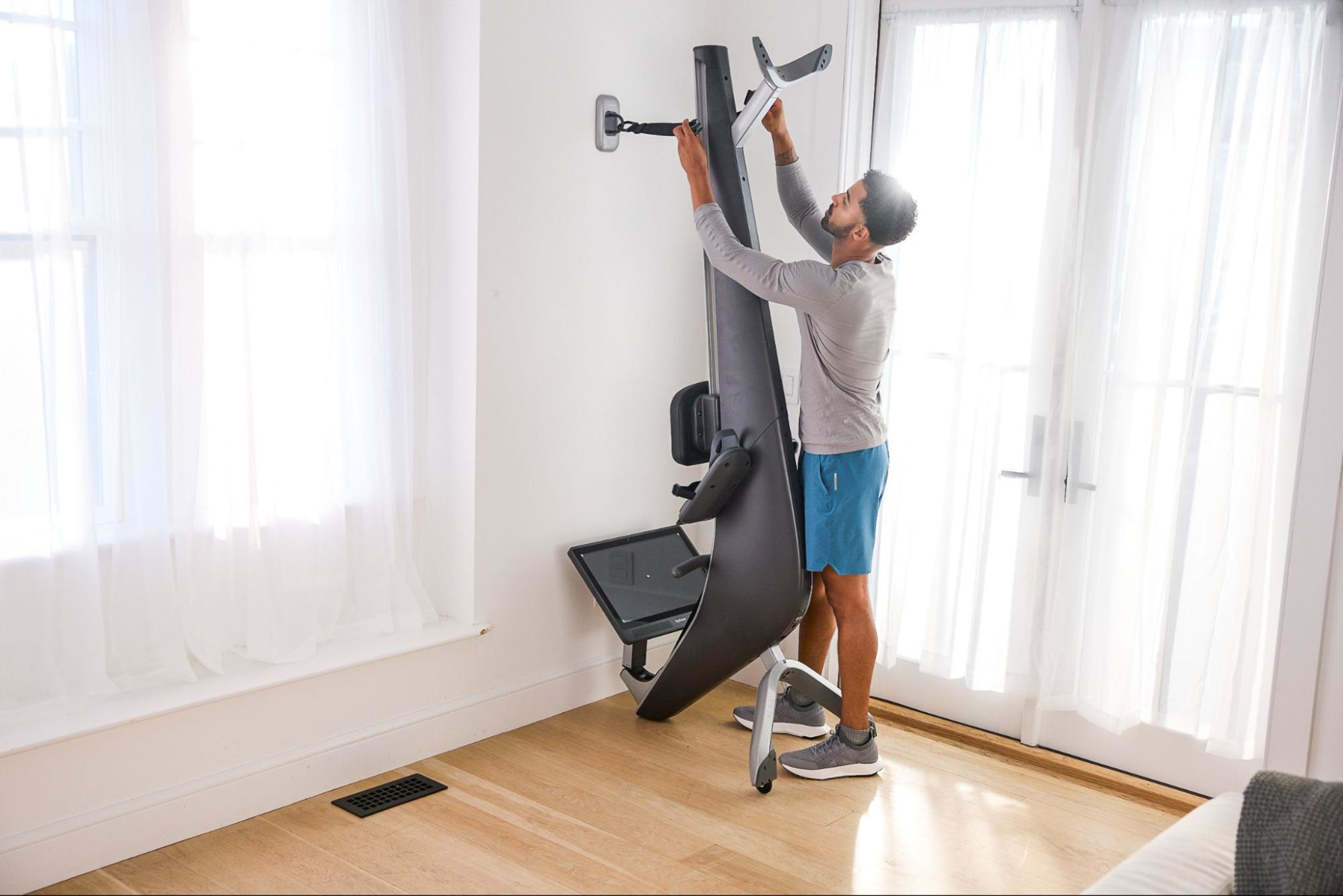 Man stores his Hydrow rowing machine after asking questions before buying a rowing machine.