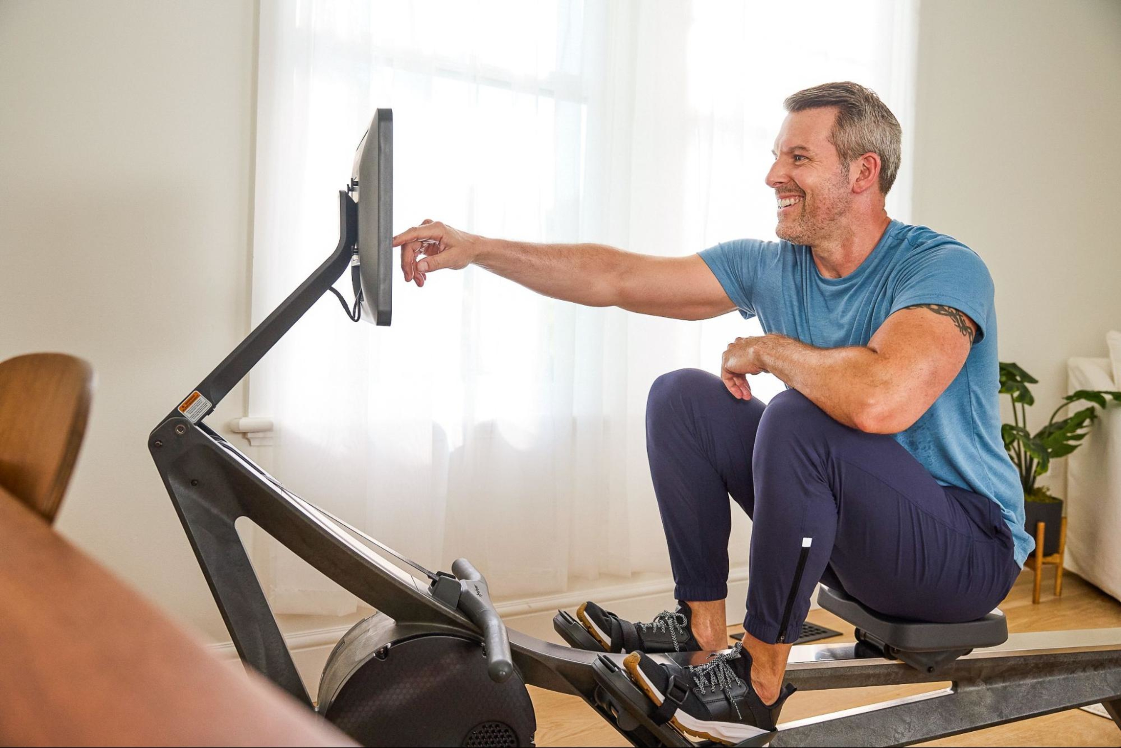 Man prepares to work out on his Hydrow rowing machine after asking questions before buying a rowing machine.