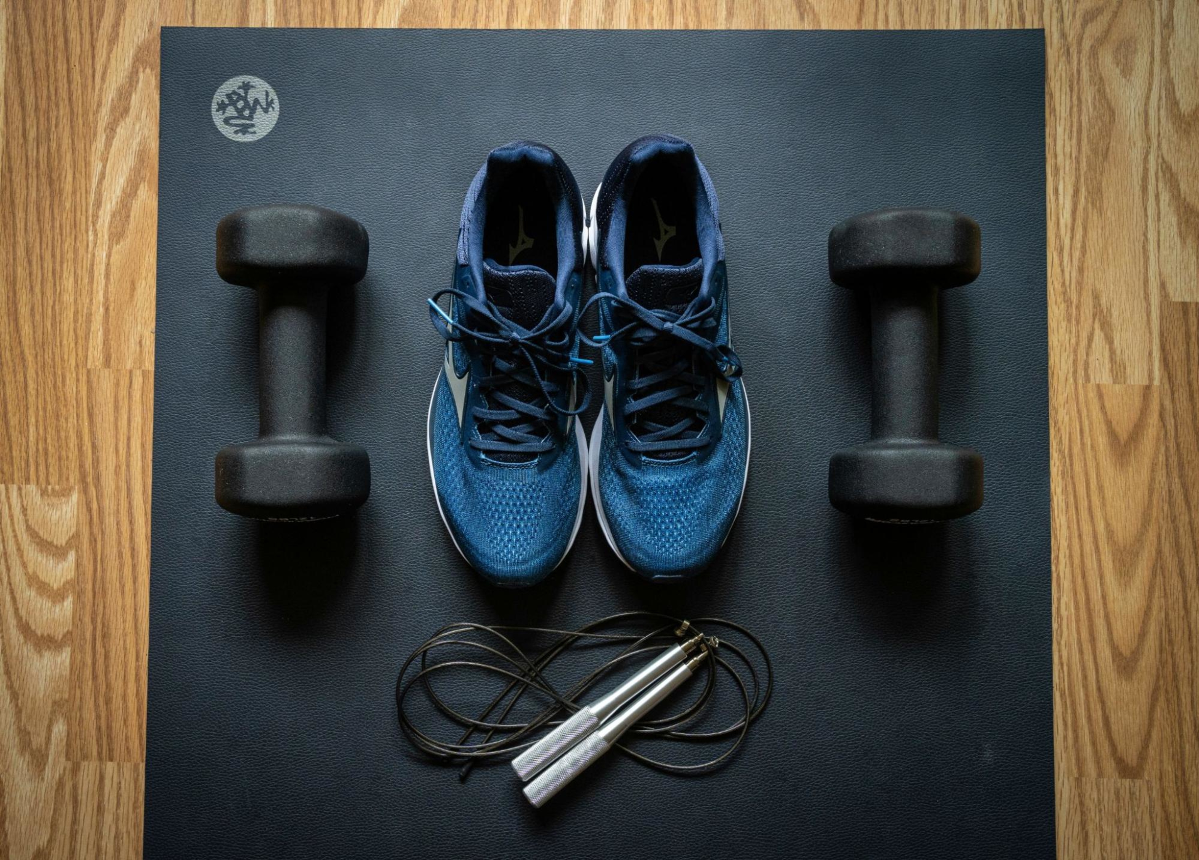 Shoes, dumbbells, and jump ropes on a yoga mat.