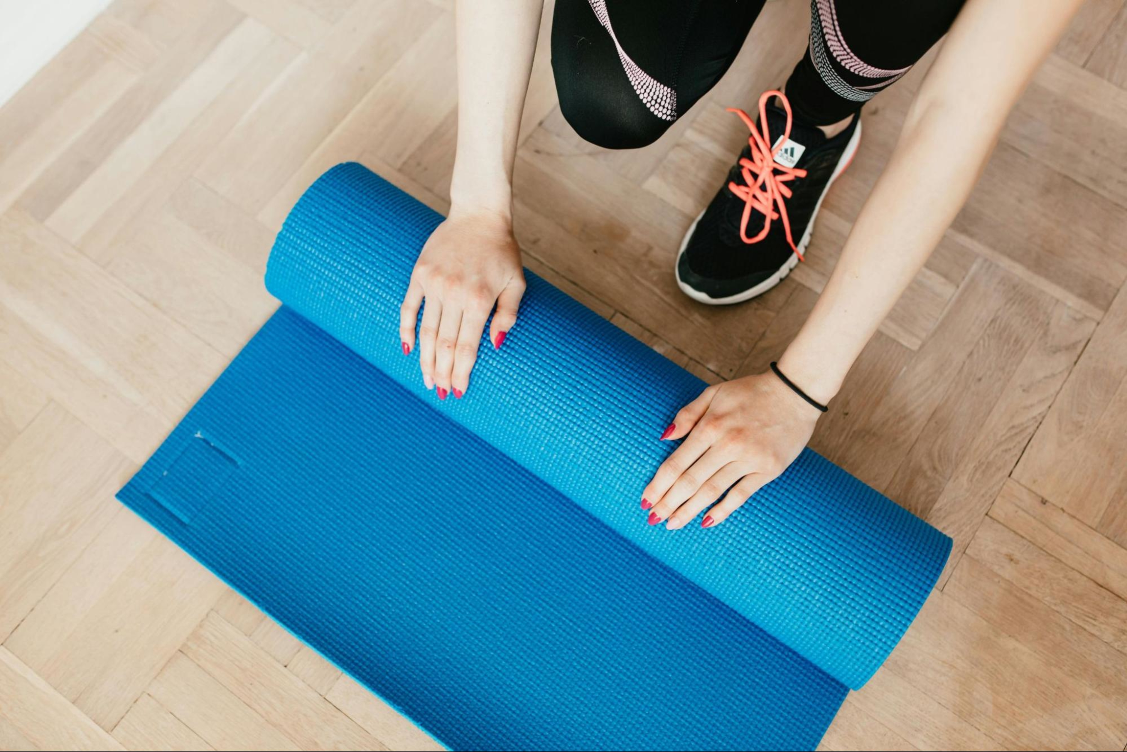 Woman rolls up a yoga mat after deciding between a home gym and a gym membership.
