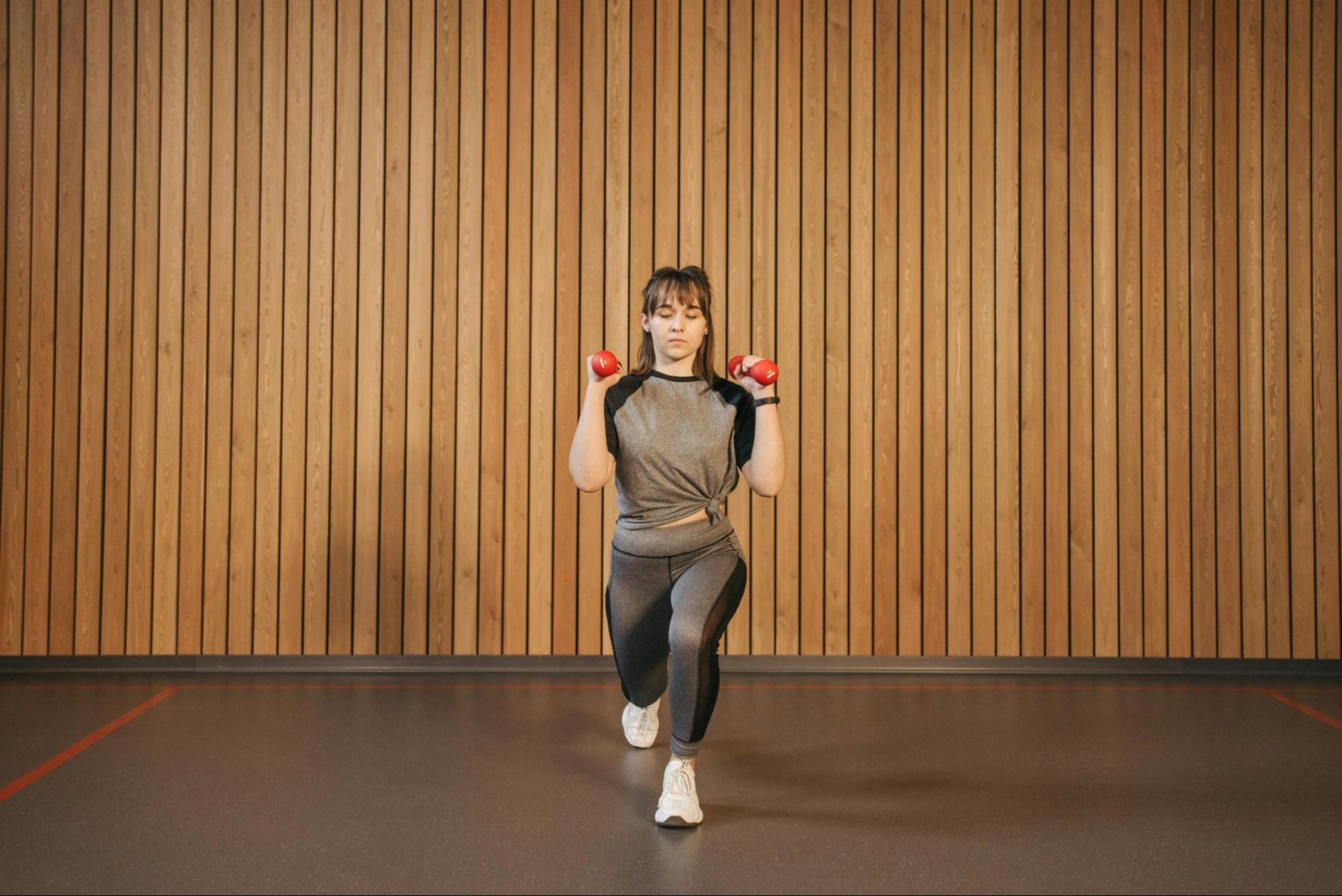 Woman works out with weights in her home gym after learning about the benefits of creating a home gym.