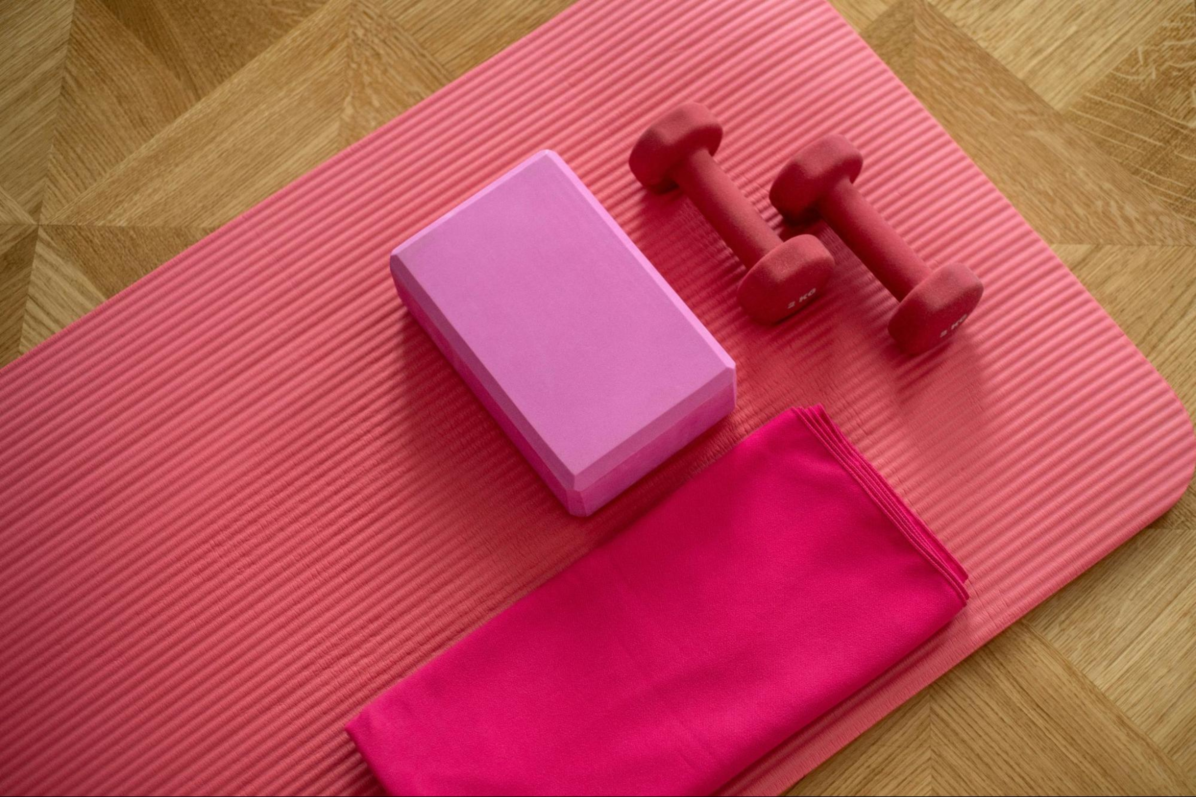 A yoga mat, yoga block, dumbbells, and towels, all essential home gym equipment.